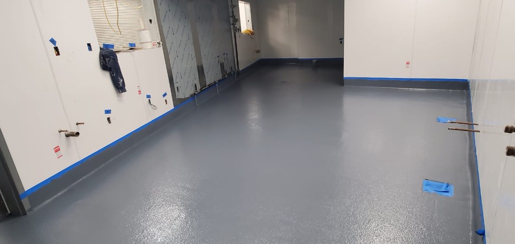 Fresh grey epoxy-coated floor with coving in a commercial room under renovation