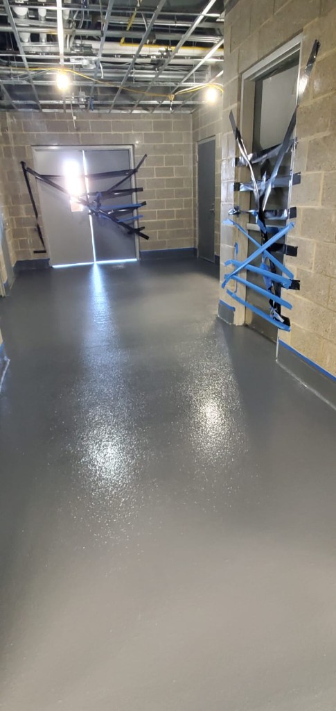 Reflective grey epoxy hallway in a block-walled building under renovation