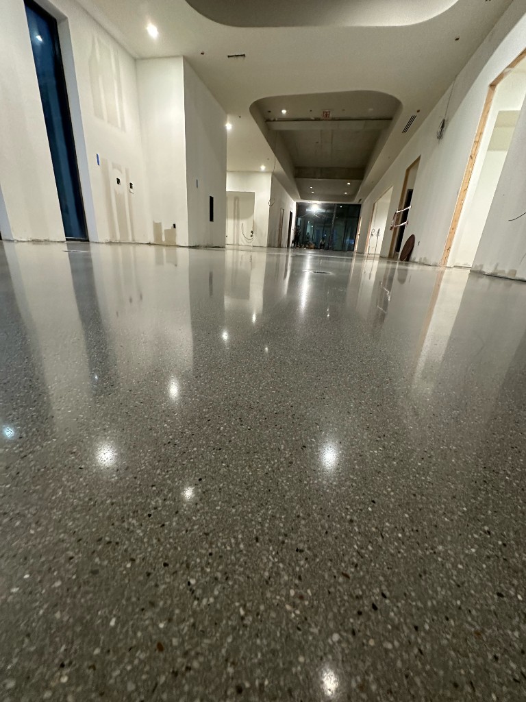 Highly polished grey concrete flooring with aggregate in a modern commercial interior